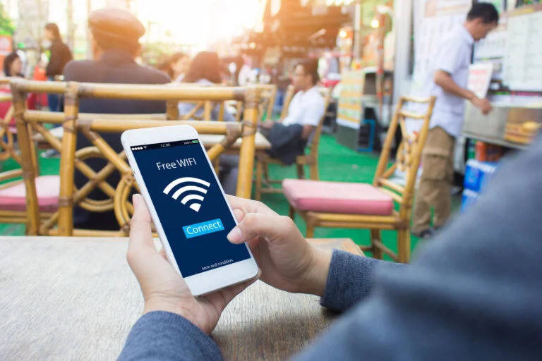 pessoa mexendo em celular com free wifi sentado em uma cafeteria ao ar livre