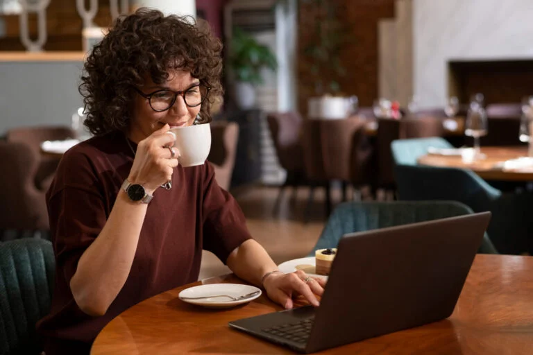 Mulher tomando uma xícara de café enquanto trabalha em um dos melhores cafés para trabalhar em Belo Horizonte.