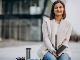 Young girl sitting reading book and drinking coffee outside the street