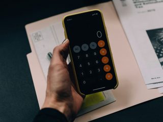 Pessoa com calculadora na mão trabalhando em gestão de orçamento.