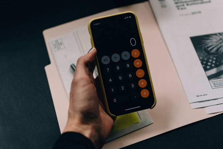 Pessoa com calculadora na mão trabalhando em gestão de orçamento.