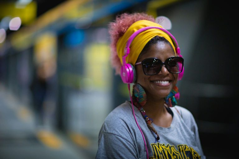 Manual viajante neurodivergente: mulher negra sorrindo com fone de ouvido.